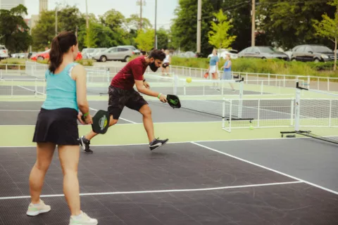 pickleball player returns a serve while his partner watches