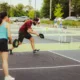 pickleball player returns a serve while his partner watches
